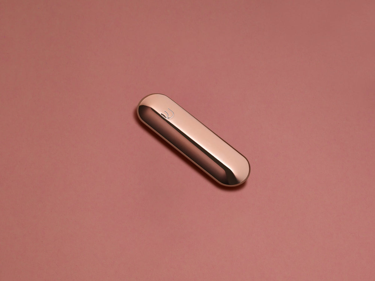 Rose Gold Pill Mezuzah shown at an angle against a blush background