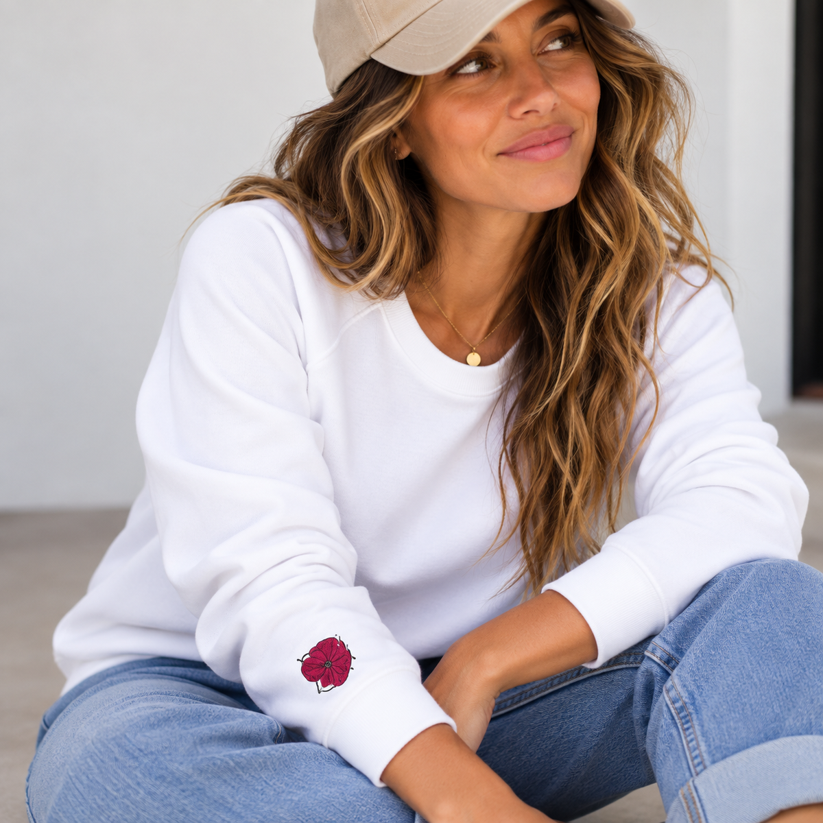 Woman wearing the white Poppy Lane Poppy Sweatshirt with embroidered poppy on the sleeve