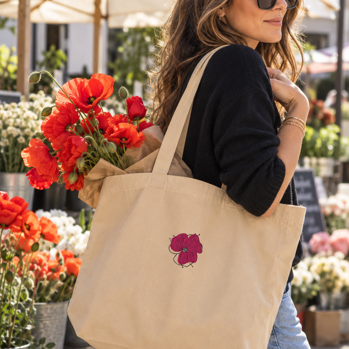 - Alt: Woman carrying embroidered poppy canvas tote filled with fresh poppies