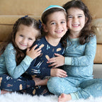 Three children in pajamas sitting together on a couch