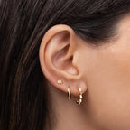 Small 14K gold huggie earring worn in a layered ear stack