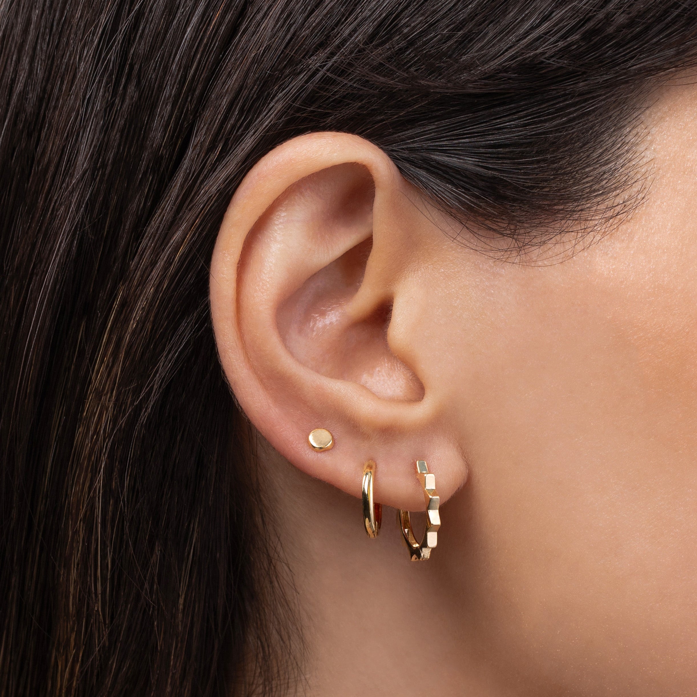 Small 14K gold huggie earring worn in a layered ear stack