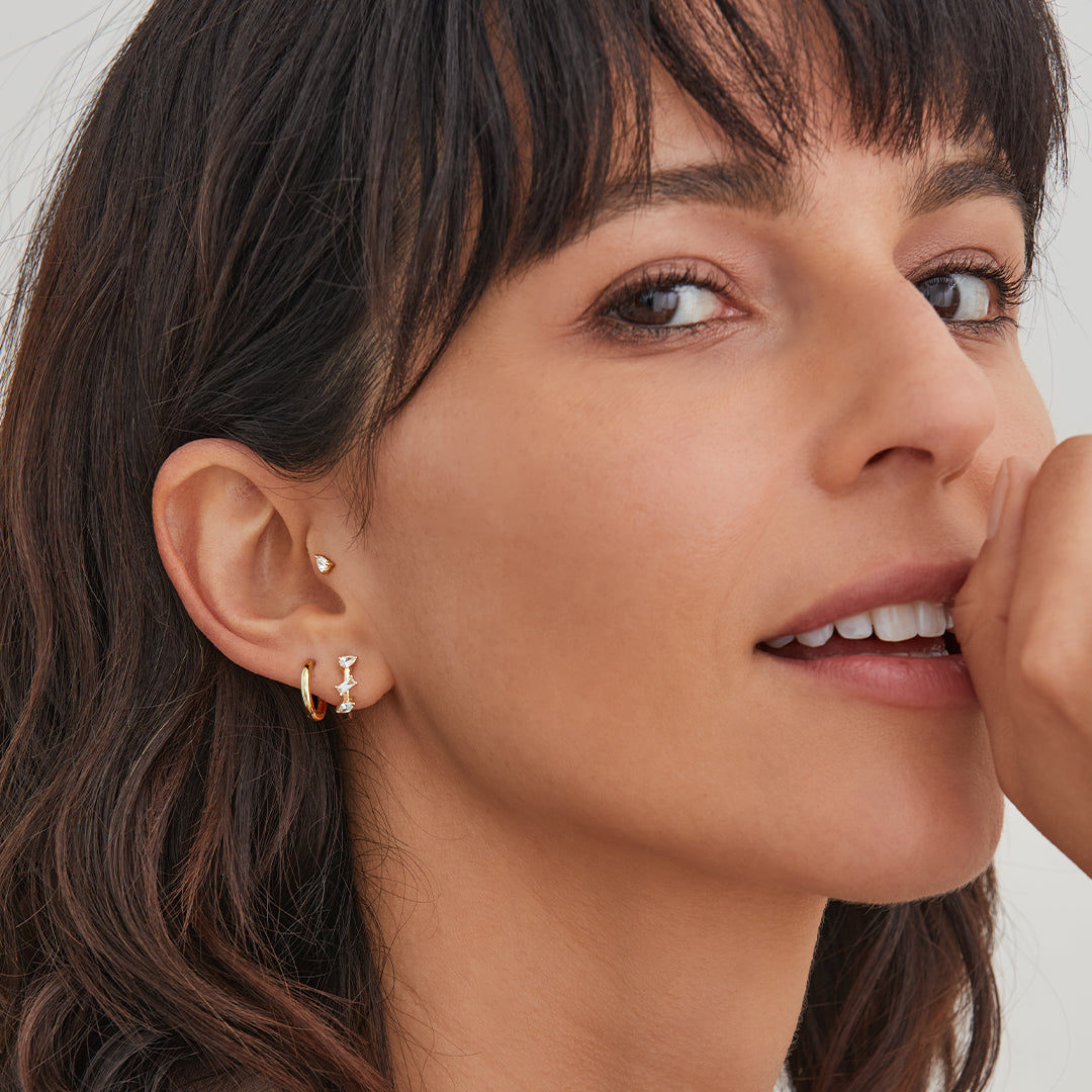 Small 14K Gold Huggie Earrings shown on ear for scale