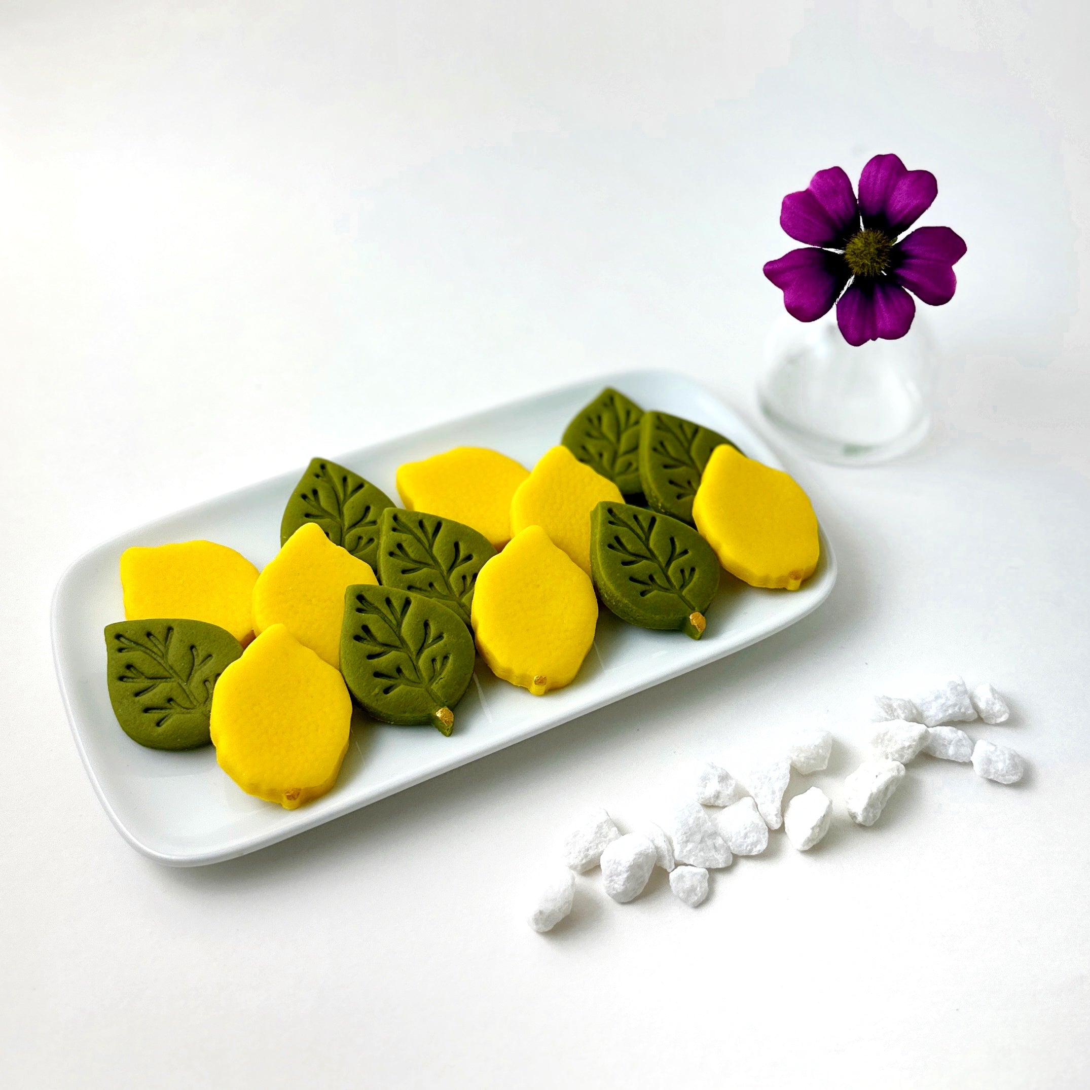 Sukkot marzipan etrogim and embossed green leaves arranged on a serving platter