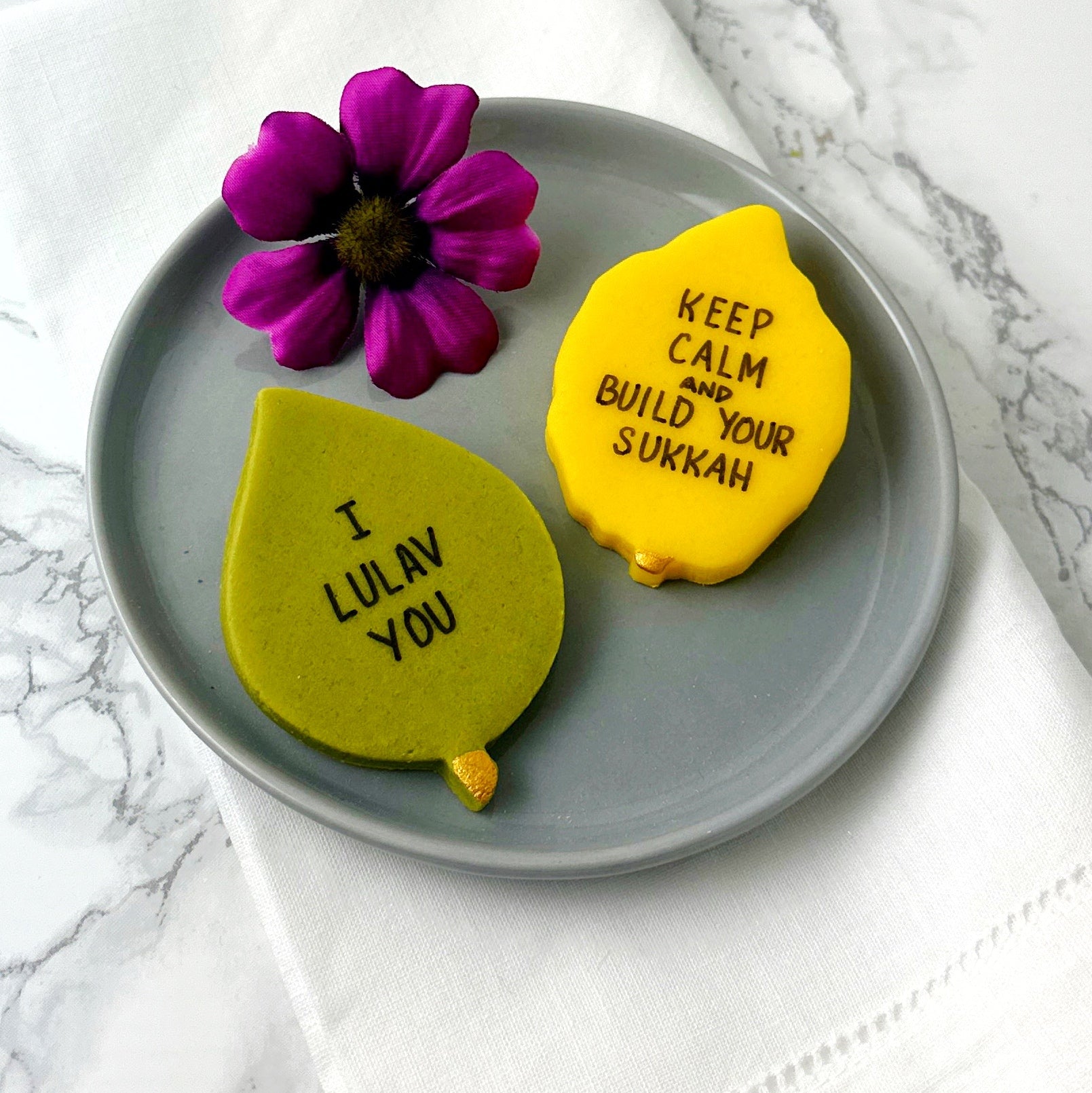 Three Sukkot marzipan conversation tiles with hand-drawn holiday puns served on a plate by Marzipops