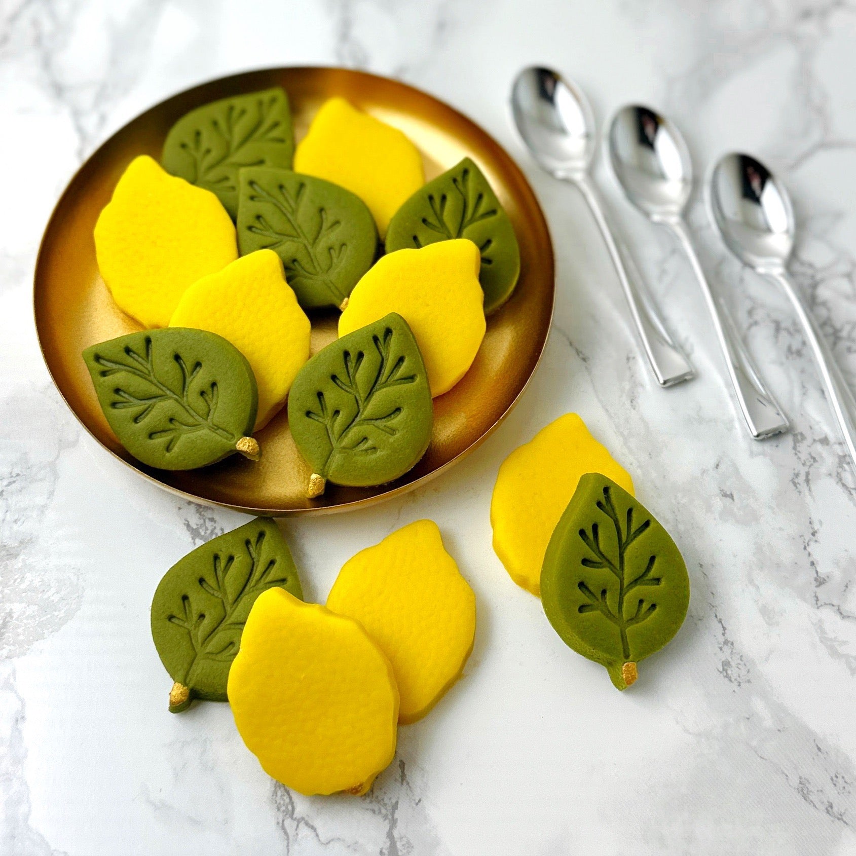 Handcrafted marzipan etrogim and green leaves served on a gold plate for Sukkot