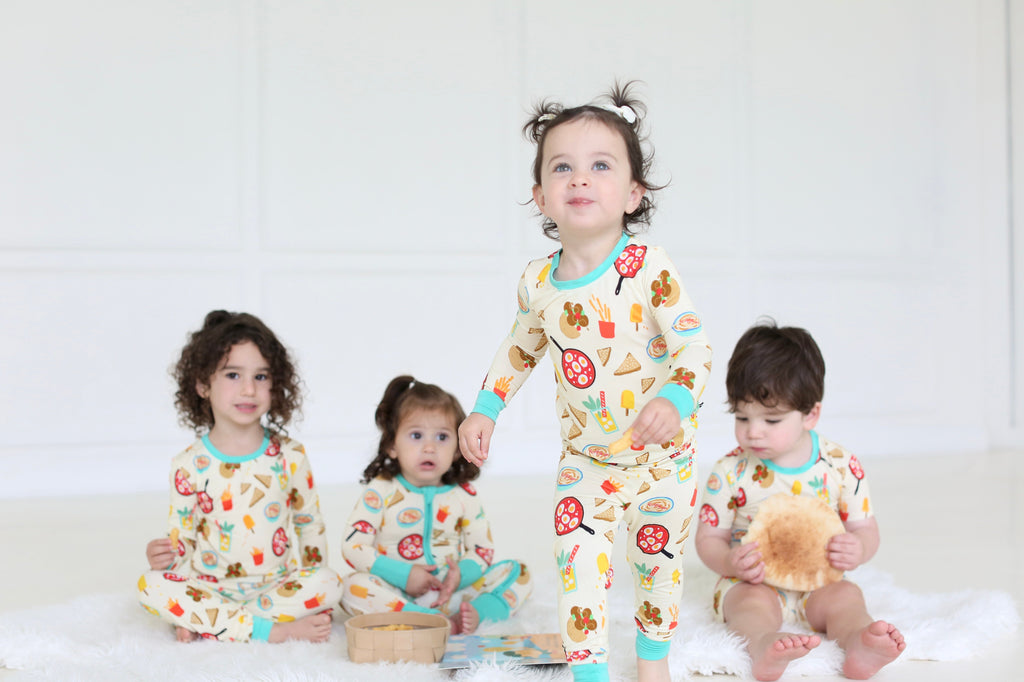 Children in coordinating Taste of Israel two-piece pajamas and baby zippy