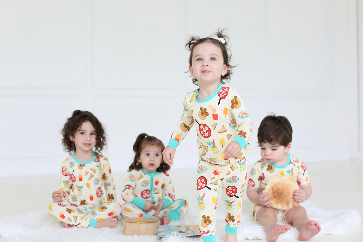 Children in coordinating Taste of Israel two-piece pajamas and baby zippy