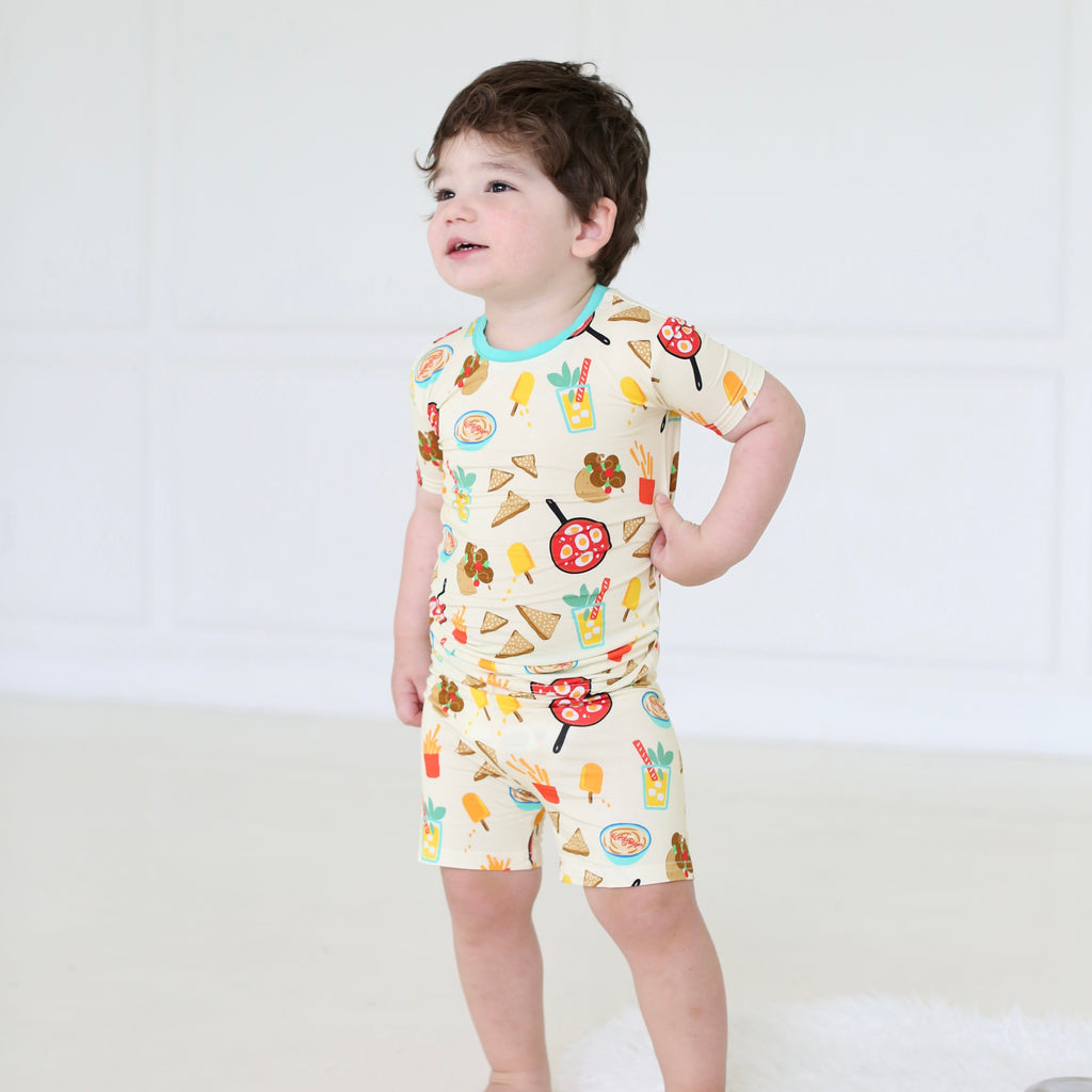 Young boy wearing the Taste of Israel short-sleeve pajama set with playful Israeli food illustrations