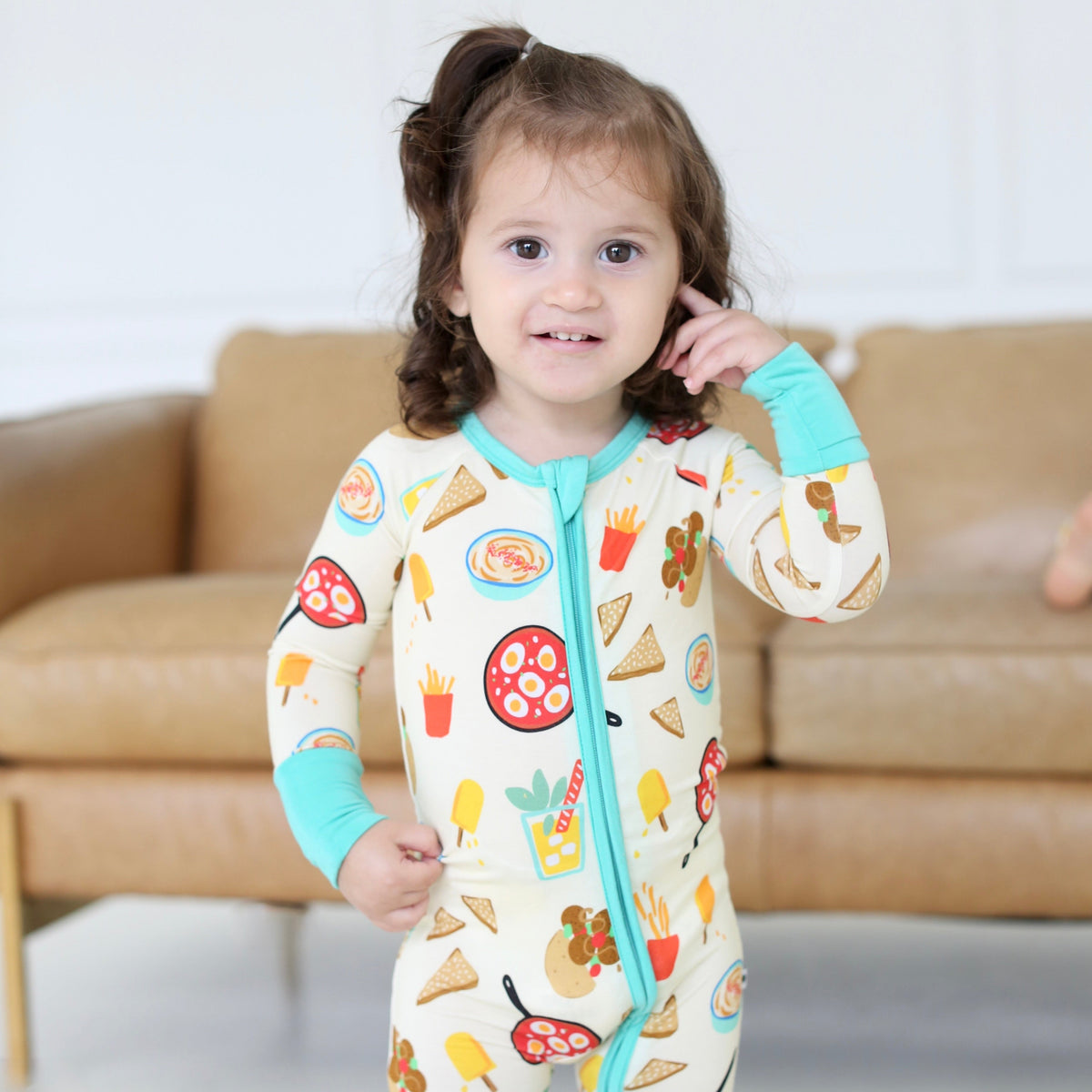 Young child wearing the Taste of Israel zippy with playful Israeli food illustrations