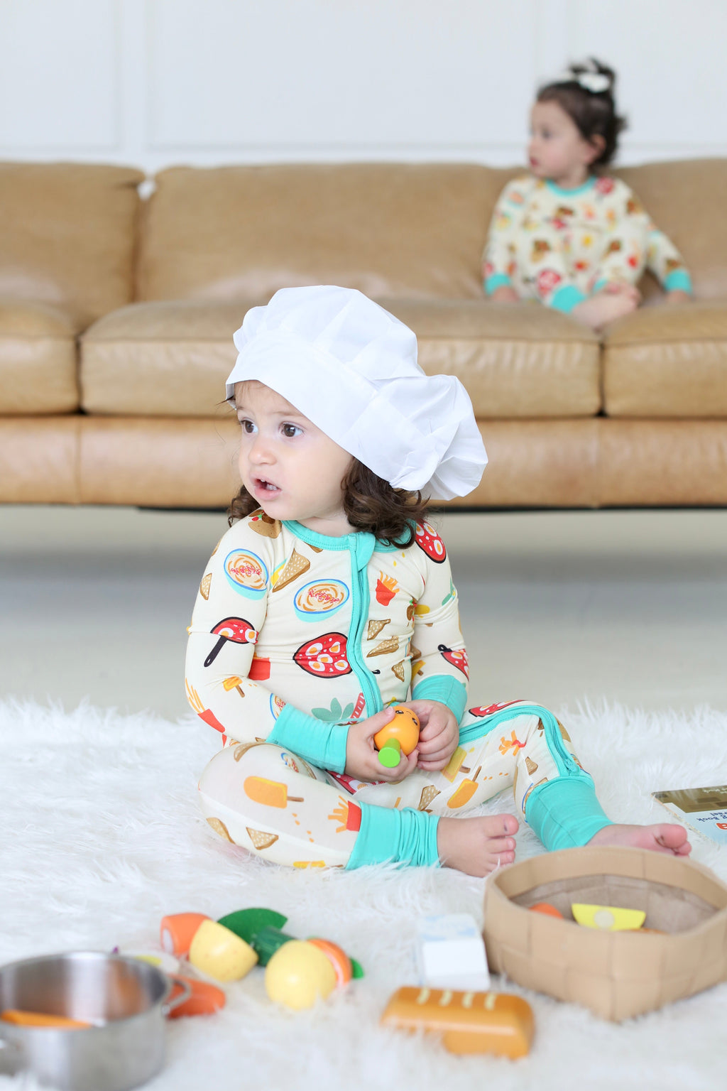 Child in the Taste of Israel zippy wearing a chef hat and playing with toy food