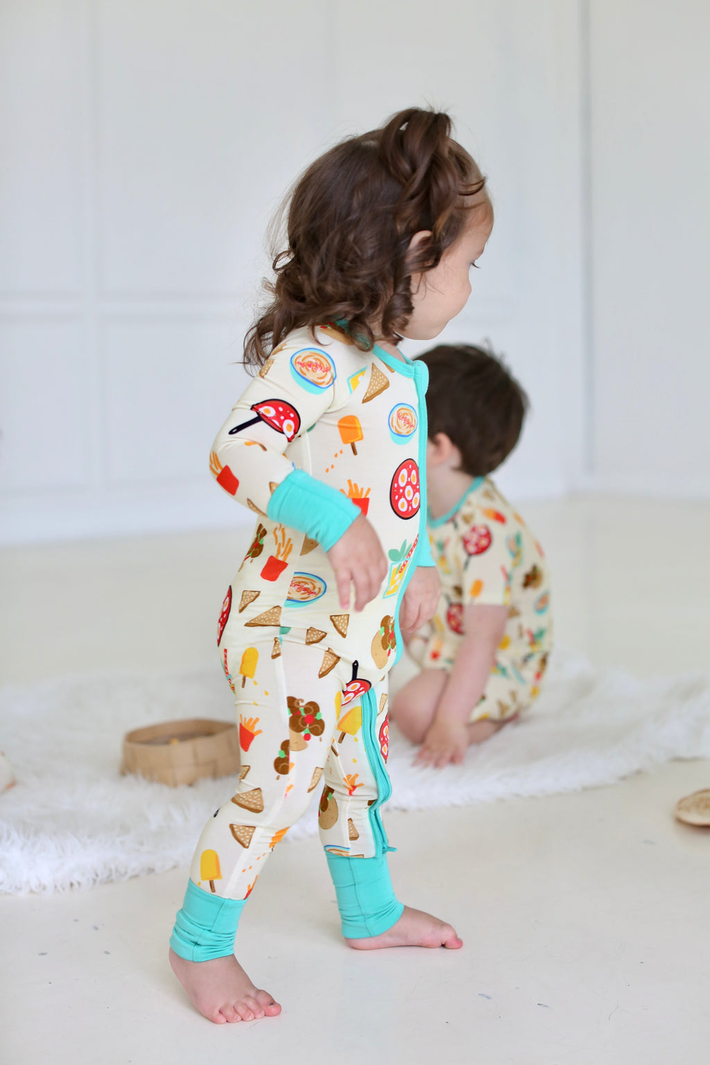 Side view of child wearing the Taste of Israel zippy with aqua trim