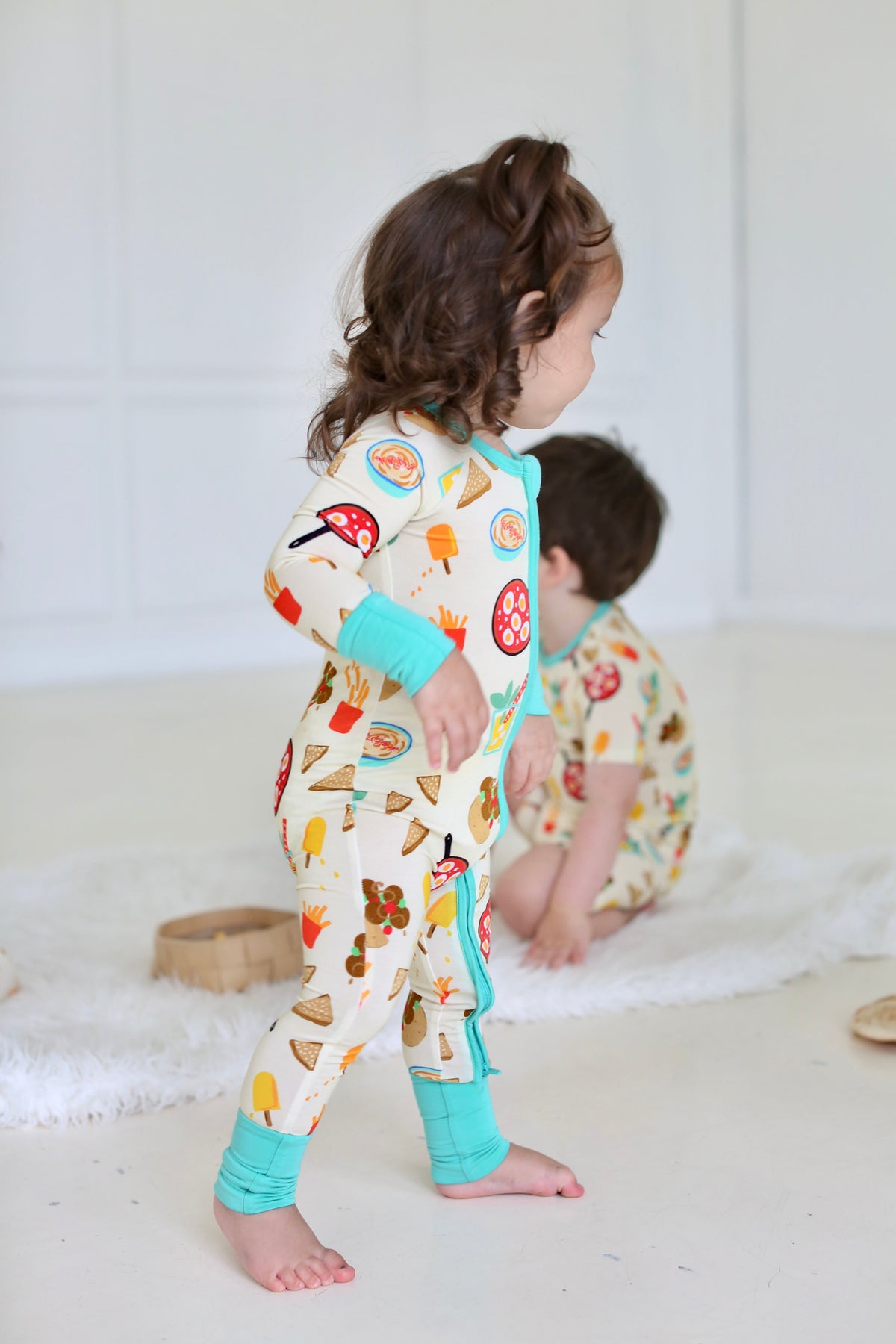 Side view of child wearing the Taste of Israel zippy with aqua trim