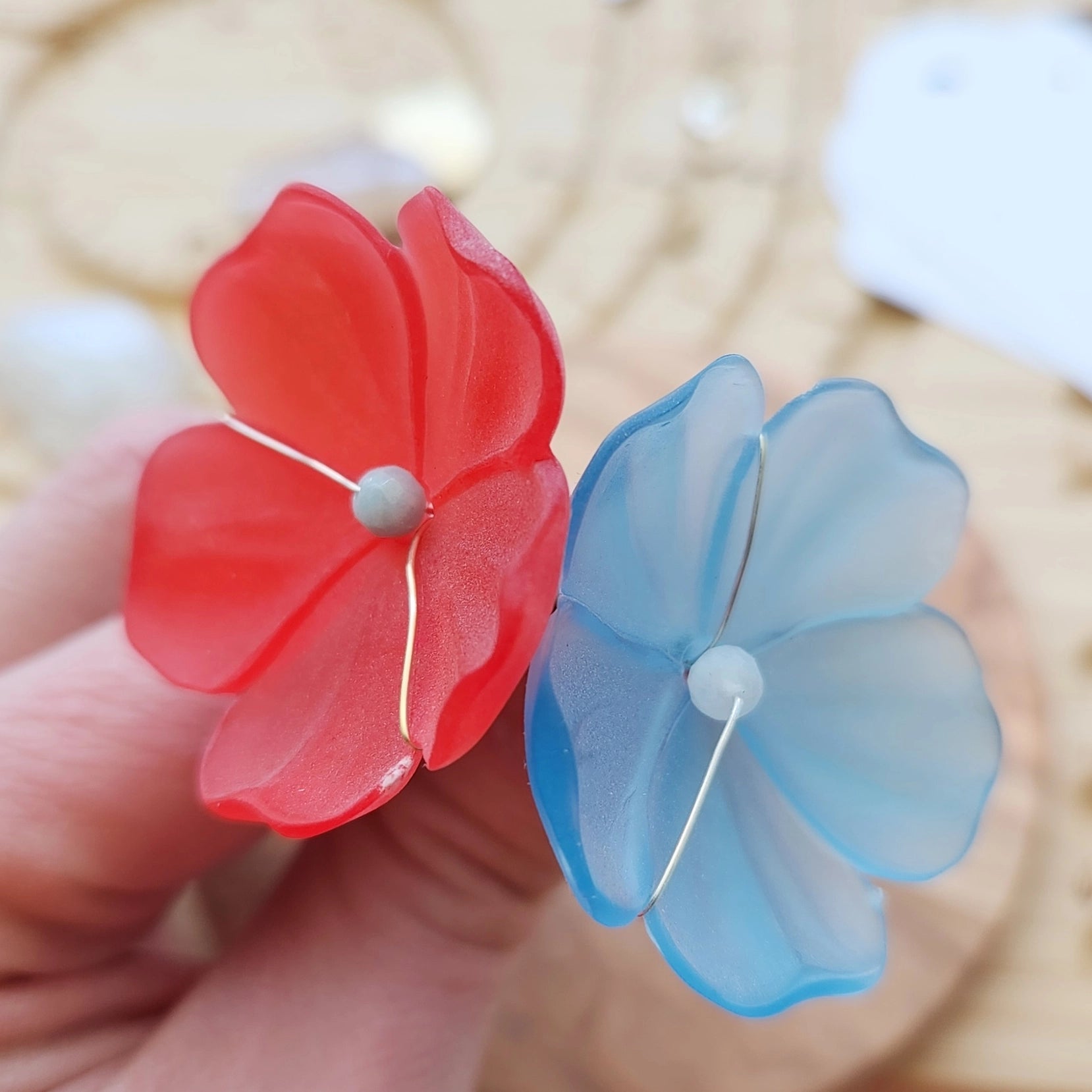 Blue and berry red lucite poppy hairpins held in hand